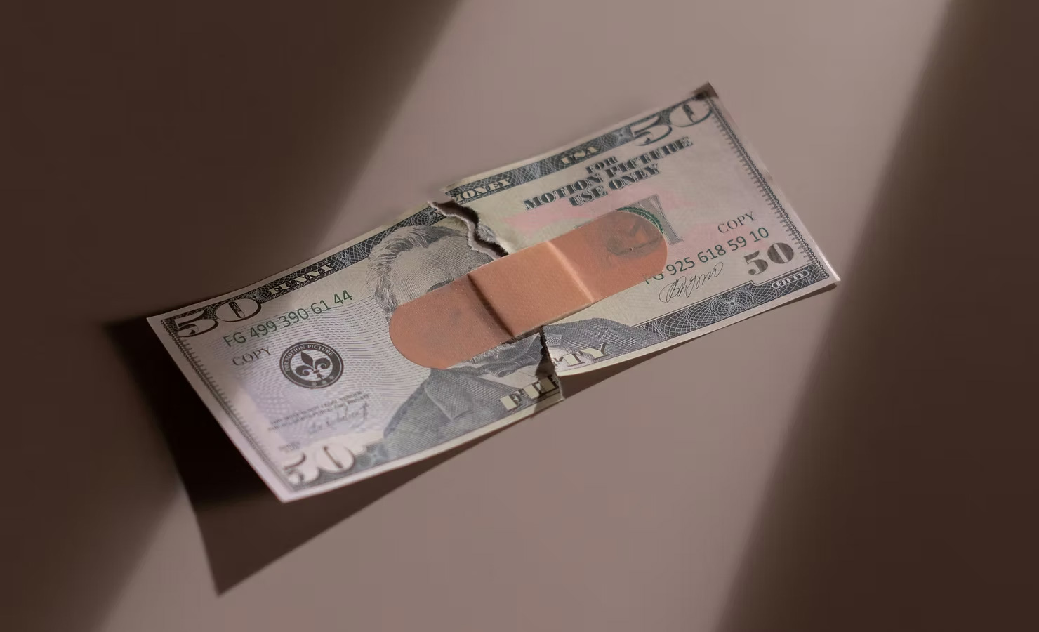 Nota de US$ 50.00 rasgada no meio com um band-aid remendando.