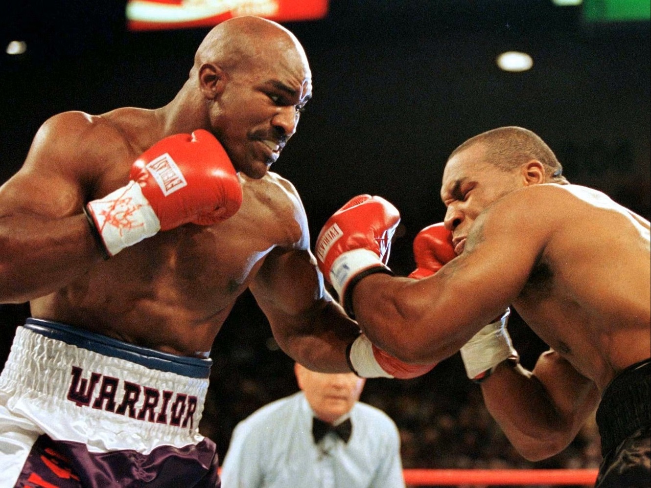 Foto do confronto histórico entre os pugilistas peso-pesados Evander Holyfield e Mike Tyson. Ilustra a famosa frase de Tyson, dizendo que "todo mundo tem um plano até levar um soco na cara"