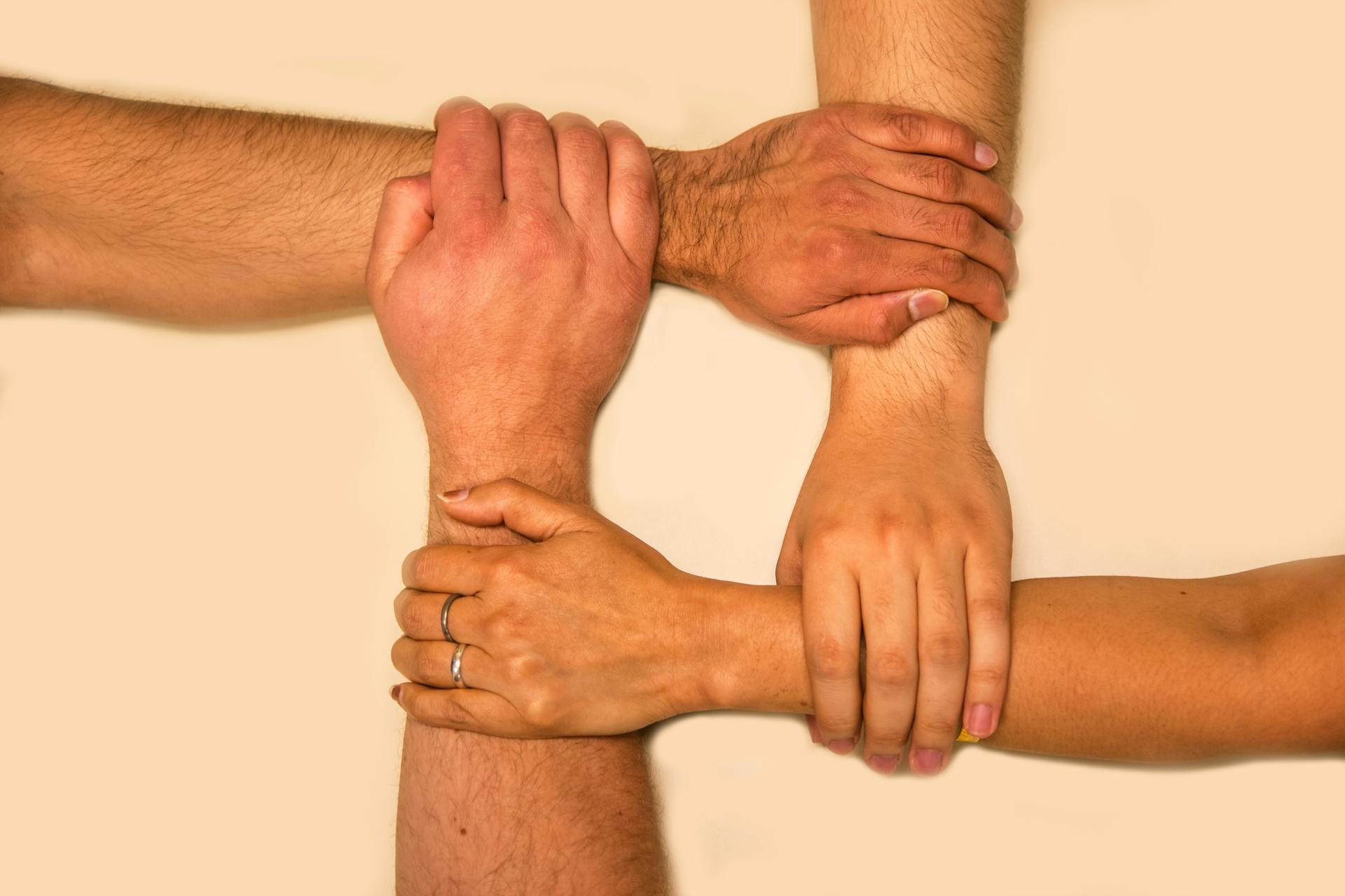 Quatro mãos, uma segurando no pulso da outra em sequência, formam um quadrado. FOTO: Mohan Nannapaneni, via Pexels